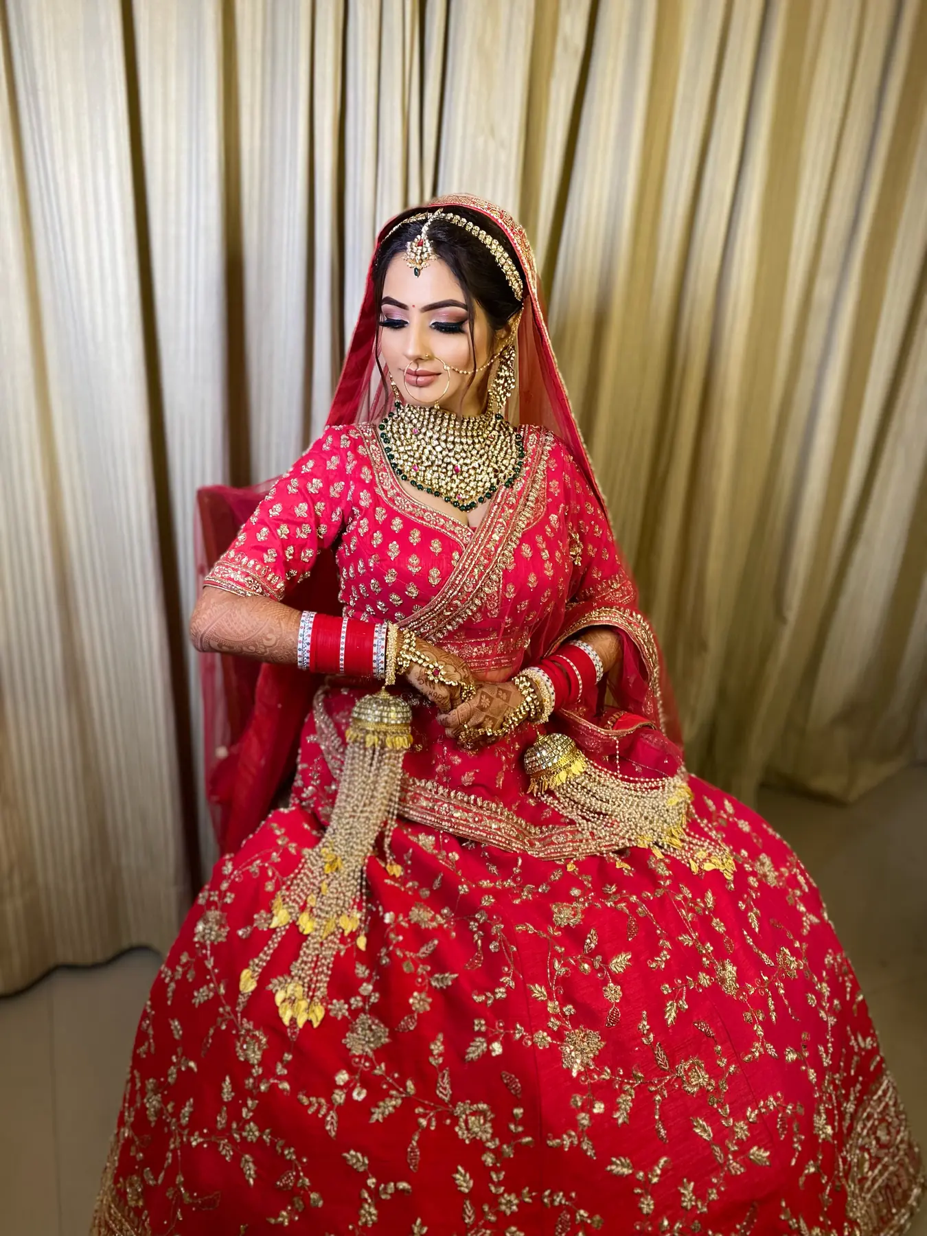 Bride in a red lehenga and gold veil, bridal makeup by MG Makeovers, Gurugram